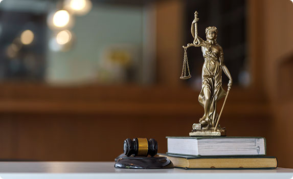 Statue of lawyer standing on top of stacked books - The Law Offices of Timothy Connors
