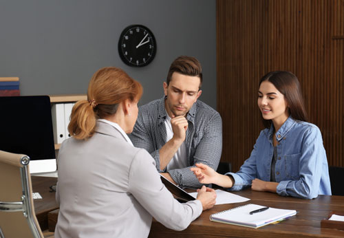 The Attorney discusses family law matters with a man and a woman at a desk in a professional setting. - The Law Offices of Timothy Connors