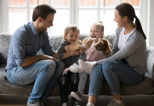 A family gathered on a couch, smiling with a stuffed animal, symbolizing family law matters. - The Law Offices of Timothy Connors
